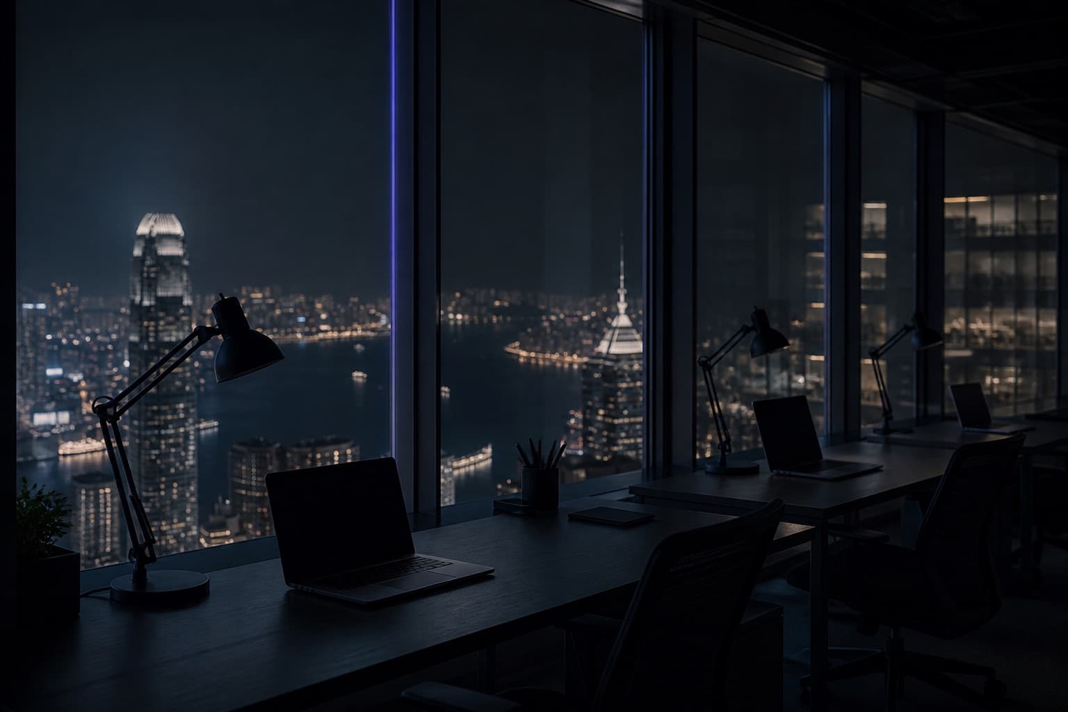 Quiet high-rise studio after hours, desks along a glass wall